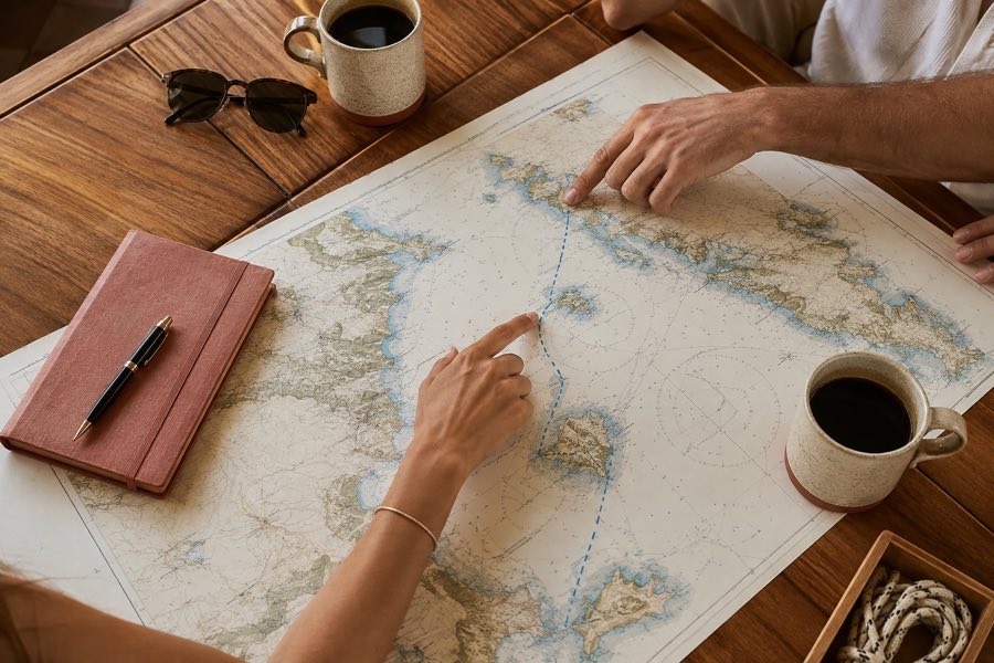 Couple planning a Greek honeymoon yacht route at a chart table