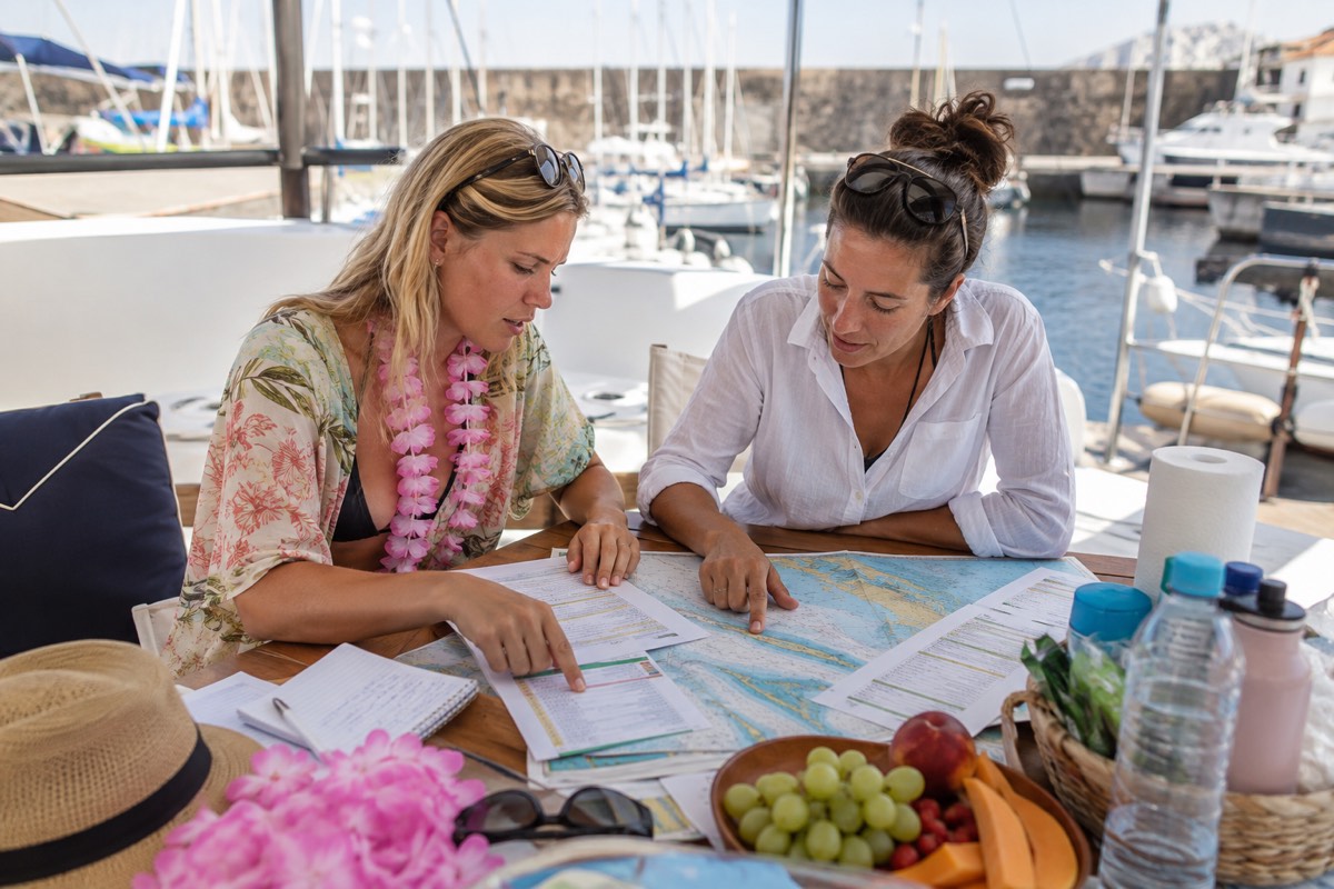 Hen party organizer and skipper checking a yacht itinerary and weather backup
